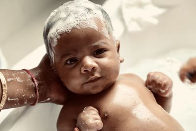 Cropped hands of mother bathing newborn baby at home