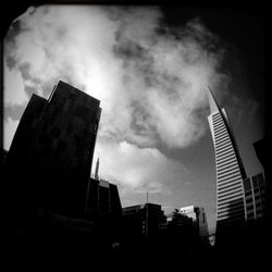 Low angle view of modern buildings against cloudy sky