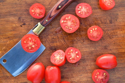 Cut grape tomatoes on wood cutting board with mini cleaver kitchen blade utencil