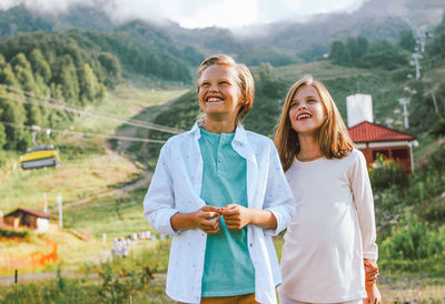 Portrait of smiling sibling standing against mountain