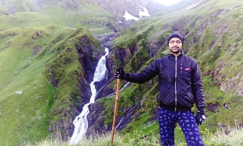 Young man standing by waterfall