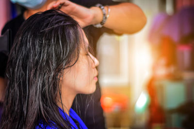Midsection of hairdresser drying woman hair in salon