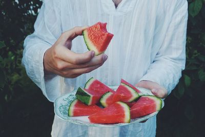 Midsection of man holding watermelons in plate