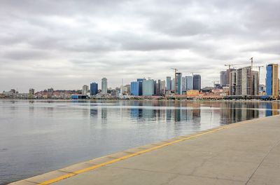 Modern cityscape by sea against sky