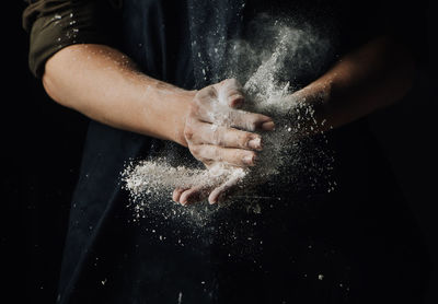 Close-up of person holding food against black background