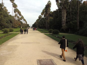 Rear view of people walking on footpath