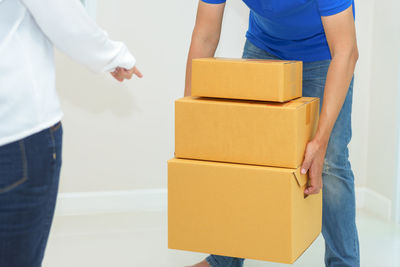 Midsection of woman guiding man holding cardboard boxes in new home