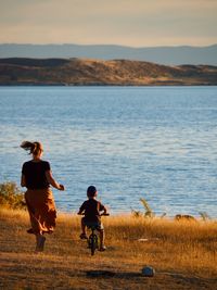 Rear view of people enjoying at shore against sky