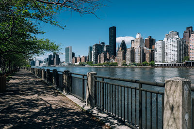 Footpath by buildings in city against clear sky