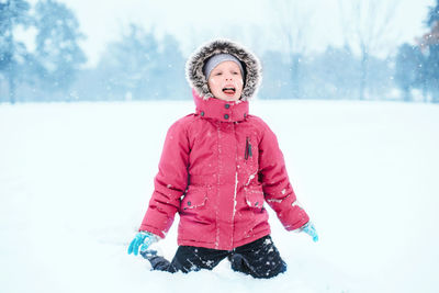 Caucasian excited girl child eating licking snow during cold winter snowy day. kids outdoor 