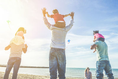 Rear view of family at beach against sky