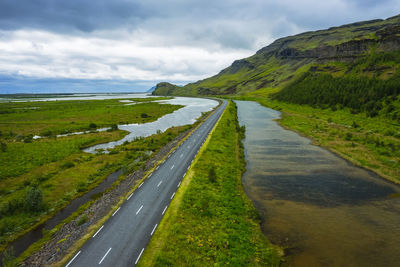 Road amidst green landscape against sky