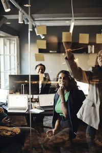 Businesswomen conducting meeting in office seen through glass