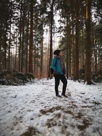 Full length of woman standing in frozen forest