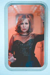 Portrait of young woman standing against wall