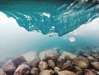 Reflection of mountains in lake with pebbles in foreground