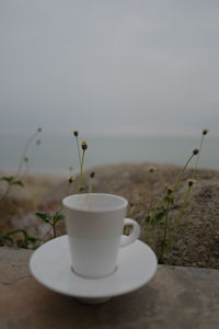 Close-up of coffee cup on table against sky