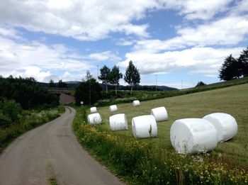 Empty road amidst field against sky