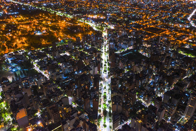 Aerial view of illuminated street amidst buildings at night