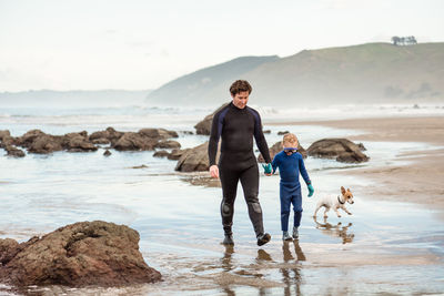 Father and young child holding hands at new zealand beach