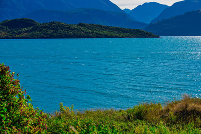 Scenic view of sea and mountains against blue sky