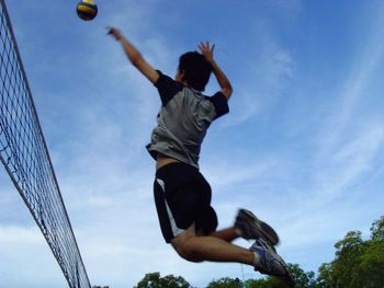 Full length of man playing volleyball against sky
