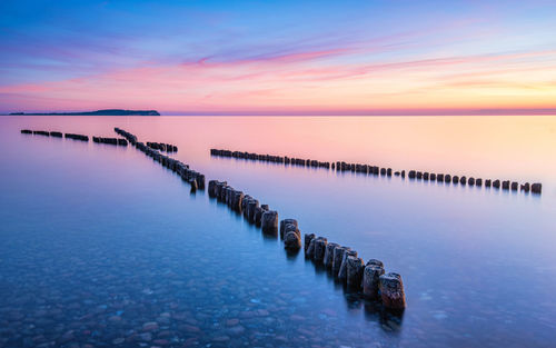 Wooden breakwaters pointing towards the sunset in dranske, ruegen, germany