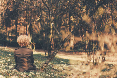 Rear view of girl with curly hair sitting in park