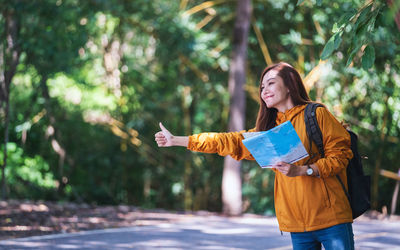 Smiling woman gesturing for hitchhiking