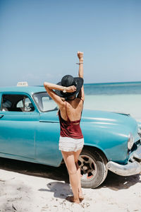 Woman standing by sea against clear blue sky