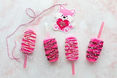 Homemade decorated valentine cakesicles with a valentine card attached to one.