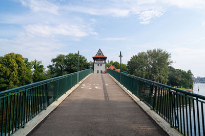 Footbridge leading towards building against sky