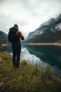 Man standing on mountain by lake against sky