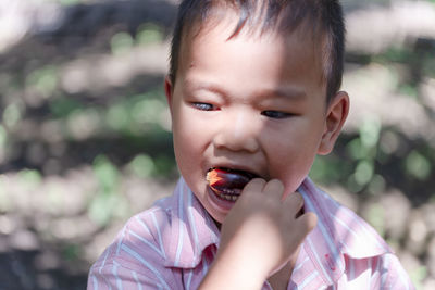 Cute boy eating fruit outdoors