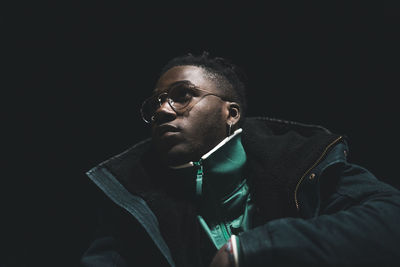 Portrait of young man against black background