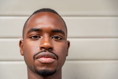 Close-up portrait of young man against wall