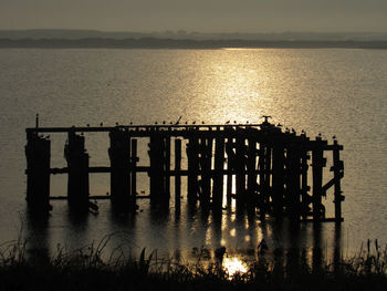 Silhouette pier on sea against sky during sunset