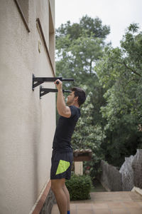 Man exercising by wall in yard