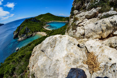 Rock formations by sea against blue sky