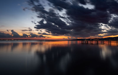 Scenic view of lake against dramatic sky during sunset