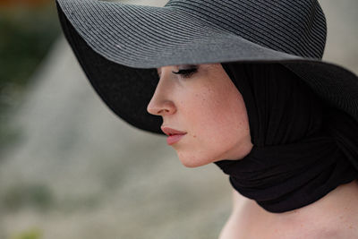 Close-up of thoughtful woman wearing black hat