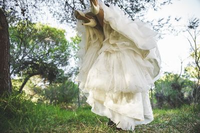 Low section of bride in wedding dress outdoors