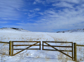 Frozen fence against sky during winter