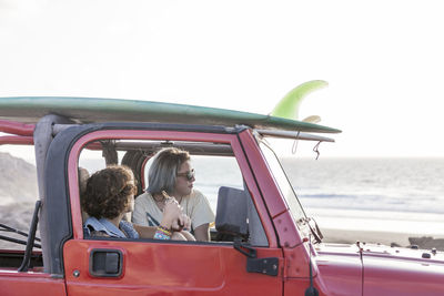 Two surfer girls with sunglasses on their 4x4 car surfboards on top
