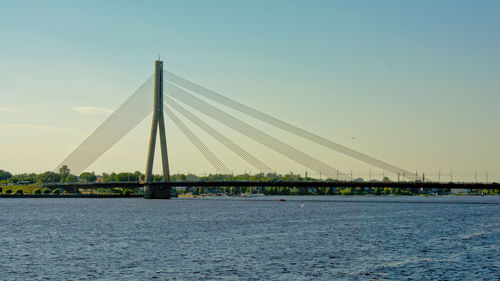 Suspension bridge over river against clear sky