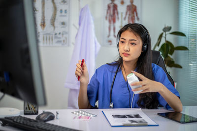 Young woman using mobile phone while sitting on table