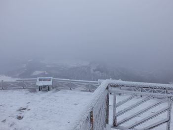 Snow covered railing against snowcapped mountain