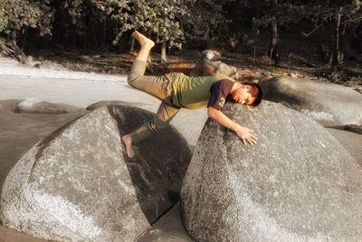 Full length of shirtless boy on rock at sea shore