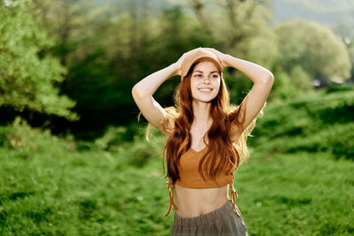 Portrait of young woman standing against trees