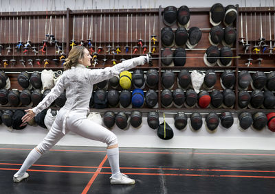 Woman in fencing outfit practicing at gym